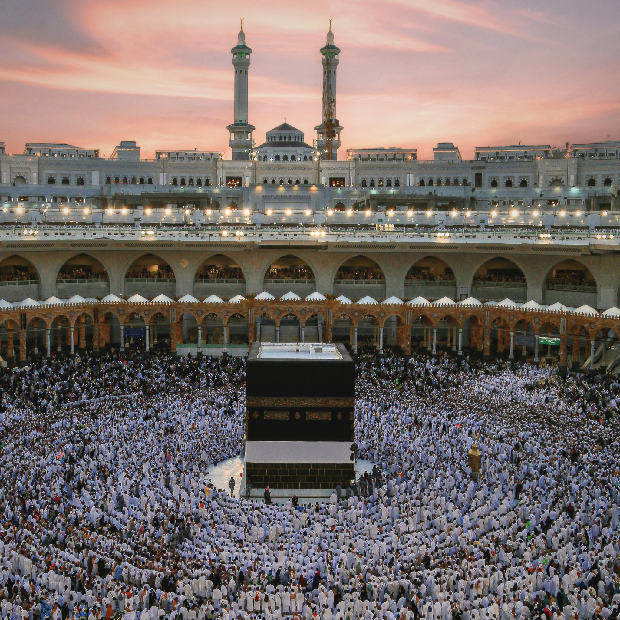 The Kaaba in Makkah at sunset during the first ten days of Dhul Hijjah, with pilgrims gathered in worship around the Sacred Mosque.